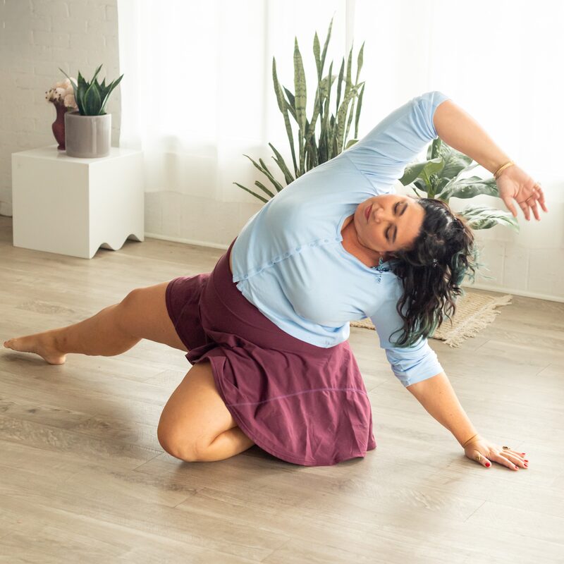 Alexandria in a floor-seated back arch, one leg extended